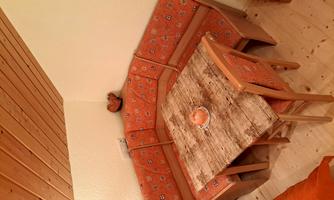 A cozy dining area with an L-shaped seating area in orange fabric. The table is made of wood and adorned with a small decoration.