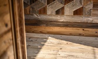 A room with wooden paneling and an elegant geometric pattern on the wall. The floor showcases natural wood textures and is filled with warm light.
