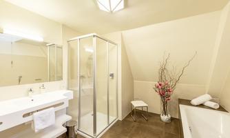 A modern bathroom with a shower and bathtub. It has a bright, friendly atmosphere and decorative flowers.