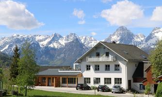 A beautiful house nestled in a picturesque mountain landscape. The snow-covered mountains and clear sky create an idyllic atmosphere.