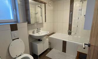 A modern bathroom with a bathtub and a sink. The room is bright and neatly furnished.