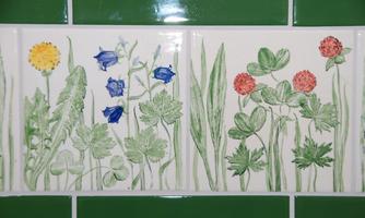 A decorative tile with colorful flowers and grasses. The designs feature a variety of plants in different colors.