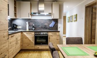 A modern kitchen with wooden cabinets and a gas stove. The table is set with green place mats and there is an open, inviting atmosphere.