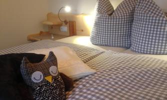 A cozy bedroom with striped pillows and an owl-shaped cushion. A soft light creates a relaxed atmosphere.