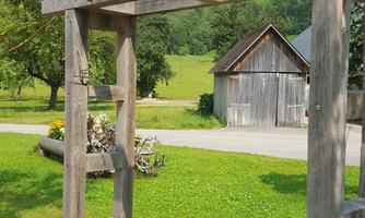A wooden cart with a beautiful view of the mountains. In the background, meadows and a wooden building can be seen.