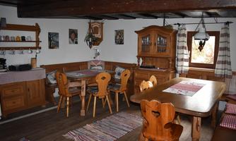 A cozy dining area with wooden furniture and rustic decoration. The room has large windows and inviting tablecloths.