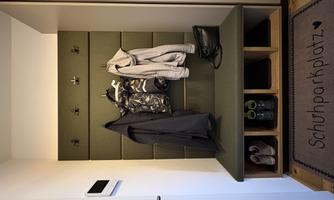 A modern entrance area with a green bench and several hooks for hanging coats. Next to the bench are shoe compartments and a doormat with the inscription "Shoe Parking."
