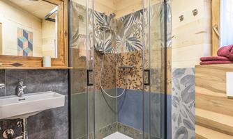 A modern bathroom with a level-access shower and elegant tiles. Wooden panels and a sink complement the cozy atmosphere.