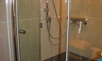A modern shower with glass walls and elegant tiles. It is well-lit and offers a comfortable showering environment.