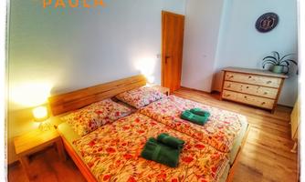 A cozy bedroom with a double bed and colorful bedding. The room has wooden flooring and a wardrobe.