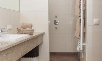 A modern bathroom with a shower and a sink. Towels are neatly placed on the shelf.