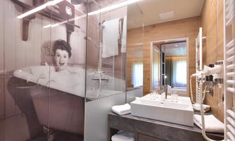 A modern bathroom with a glass shower and a large bathtub. On the wall, there is a striking picture of a smiling woman in a bathtub.