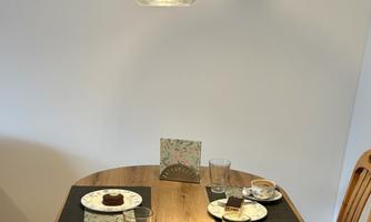 A temperate table with several set plates and glasses. In the center are small cakes and a decorative element.