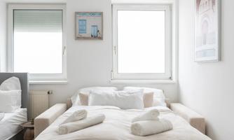 A modern room with a sleeping sofa and two windows. It is bright and minimally furnished.