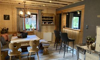 A cozy dining area with wooden paneling and modern chairs. Bright room with warm light and an inviting atmosphere.