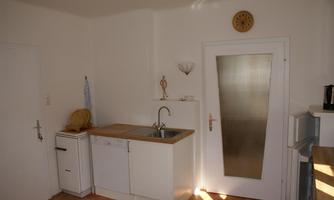 A bright kitchen with modern appliances and wooden countertops. The walls are painted in a neutral shade, and there is a window letting in light.