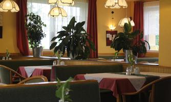 A cozy restaurant with plants and tables. The warm colors and lighting create an inviting atmosphere.