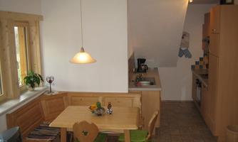 A cozy kitchen with a dining table and wooden furniture. The kitchen is bright and well-equipped.