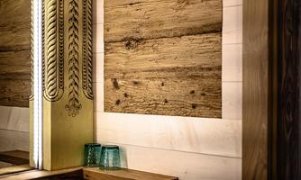 A stylish interior with rustic wooden walls. On a shelf are two green glasses.