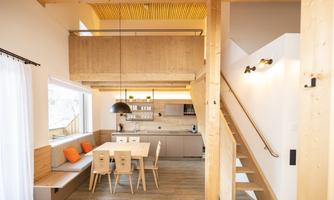 A modern and bright kitchen with wooden details and a dining table. The decor is inviting and minimalist.