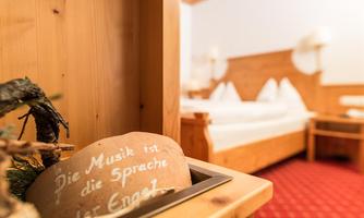A cozy bedroom with wooden decor and a red carpet. In the foreground is a decorative element with a message about music.