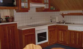 A cozy kitchen with wooden furniture and modern appliances. The walls are brightly tiled and the atmosphere is warm and inviting.