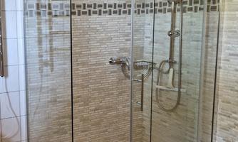 A modern shower with glass walls and a stylish tiled wall. The floor is designed with a checkerboard pattern.