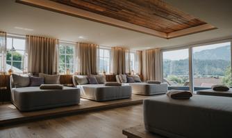 An elegant, bright room with cozy loungers and large windows. The view shows a picturesque landscape with mountains.