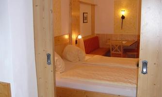 A cozy bedroom with a double bed and warm wooden elements. The room is brightly lit and creates an inviting atmosphere.