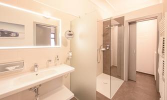 A modern bathroom with a shower and an elegant sink. The room design is bright and inviting.