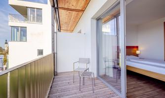 A modern balcony with two chairs and a view of a bright room. The surroundings are light and inviting.