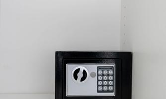 A black safe is located in a white niche. It has an electronic keypad for securing valuables.