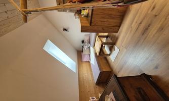 A cozy room with wooden paneling and a skylight. There is a sitting area, a small table, and a hammock.