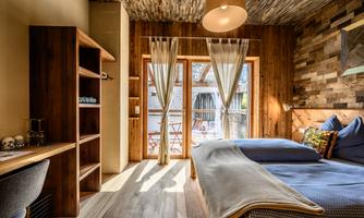 A cozy room with wood details and a large window. The decor is modern and inviting, perfect for relaxed stays.
