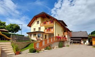 A beautiful house with a red roof and balconies. The outdoor area is landscaped with greenery and has a large driveway.