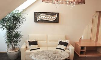 An elegant living room with a white sofa and a round table. On the wall is a modern artwork, and a plant stands in the corner.