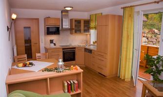 A cozy kitchen with wooden cabinets and modern appliances. Light falls through a window, creating a pleasant atmosphere.