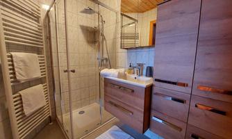 A modern bathroom with a shower and wooden cabinet. Fresh towels create an inviting atmosphere.