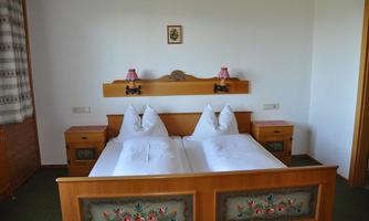 A cozy bedroom with a wooden bed and two separate mattresses. The room design is simple with green carpet and decorative nightstands.