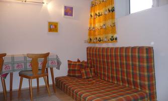 A cozy room with a checked sofa and a wooden table. Bright walls and colorful curtains create an inviting atmosphere.