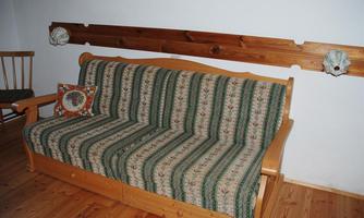 A cozy sofa with striped upholstery and a colorful pillow. In the background, a wood paneling on the wall can be seen.