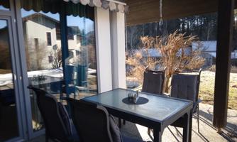 A cozy outdoor area with a table and chairs. The sunlight creates an inviting atmosphere.