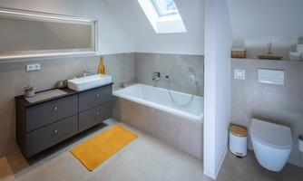 A modern bathroom with a bathtub and a sink. The walls are in neutral colors and there is a large mirror.
