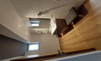 A modern bathroom with wooden floors and an elegant sink. Bright walls and large windows create a friendly atmosphere.