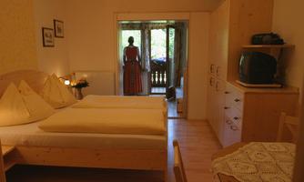 A cozy room with two beds and a beautiful view of the balcony. In the background, there is a person in traditional clothing.