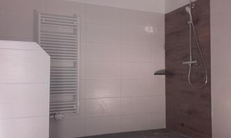 A modern bathroom with a shower and elegant tiles. A towel radiator is also visible.