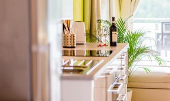 A modern kitchen with elegant appliances and a stylish cooktop. In the background, there are plants and a wine glass, creating a cozy atmosphere.