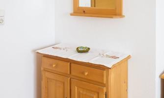 A wooden console table with two drawers and a marble top. Above it hangs a rectangular mirror on the wall.
