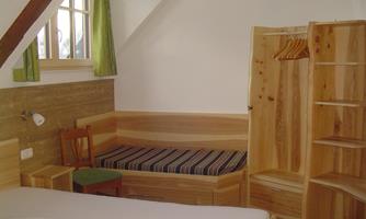 A cozy room with wooden furniture and a small seating area. Large windows let in plenty of light.
