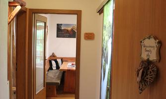 An inviting hallway with wooden doors and ceramic tiles. Light streams from a ceiling lamp into the room.